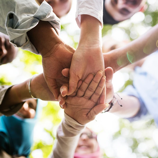 Diverse group stacking hands together: W1derus Foundation, a registered charity in Toronto