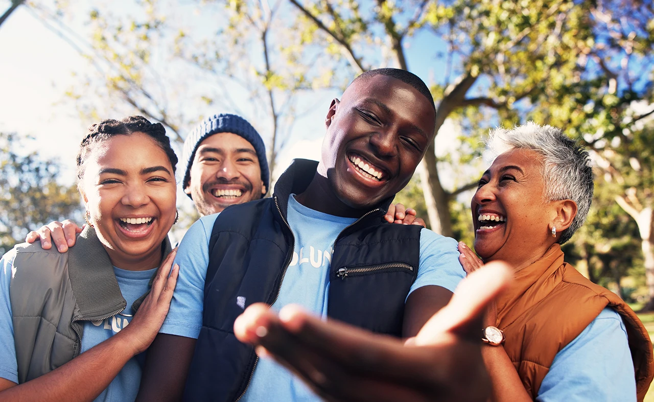 Diverse group of laughing volunteers taking a selfie outdoors: W1derus Foundation, a Toronto charity