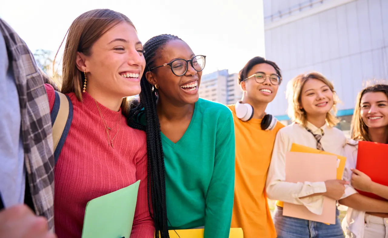 Diverse group of happy college students laughing outdoors on campus