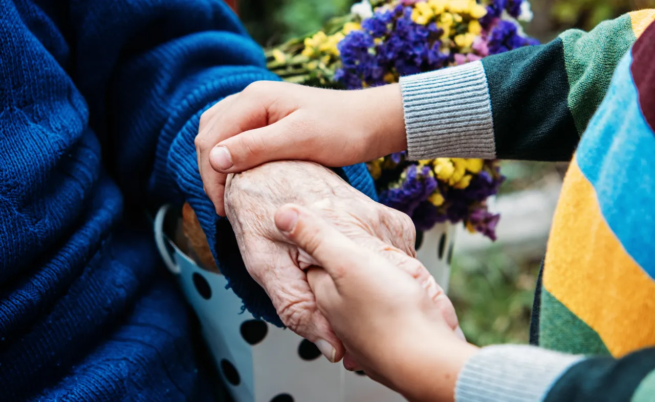 Young hands gently holding elderly person's wrinkled hands